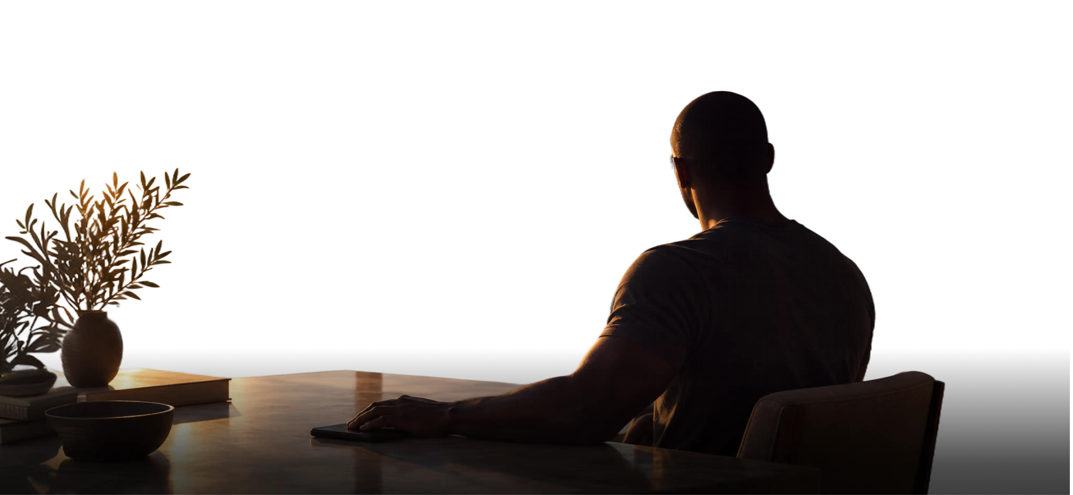A man reflecting at his desk in the morning light